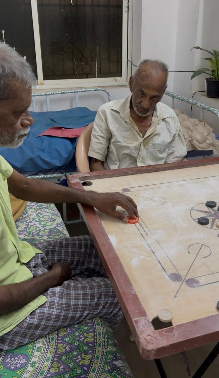 Two elderly residents enjoying a game of carrom